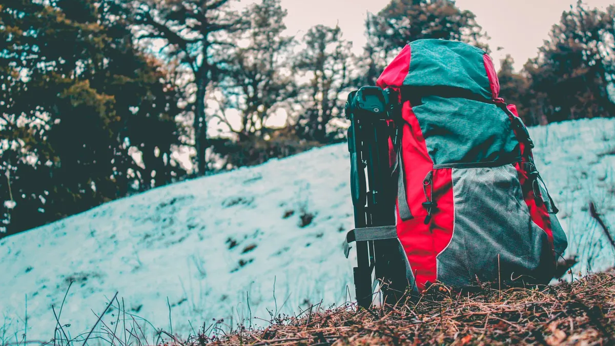 A loaded hiking backpack leaning against a truck tailgate at dusk