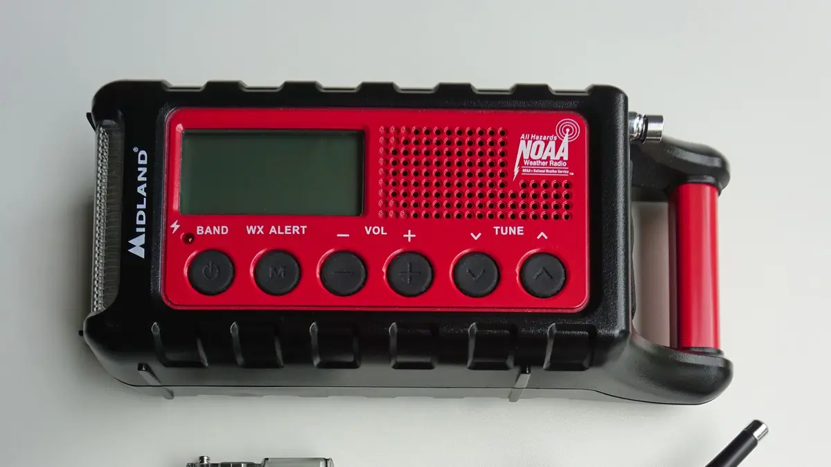 A red Midland hand crank NOAA weather radio on a white table