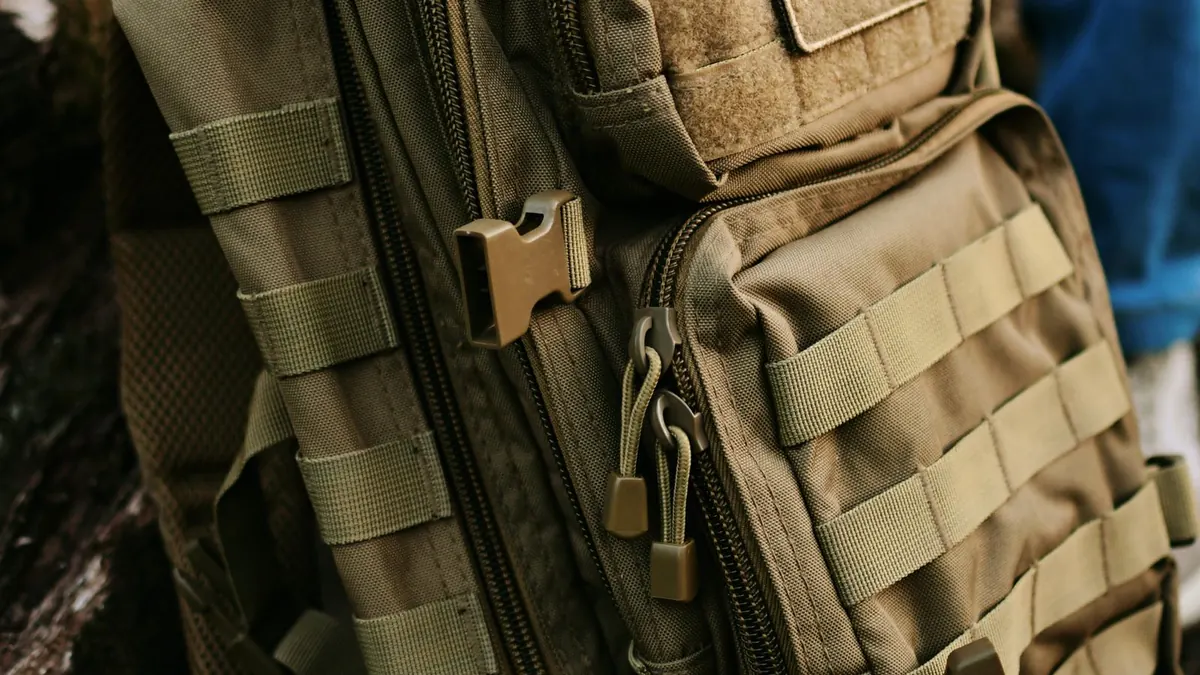 A gray tactical backpack with MOLLE webbing sitting on a concrete step