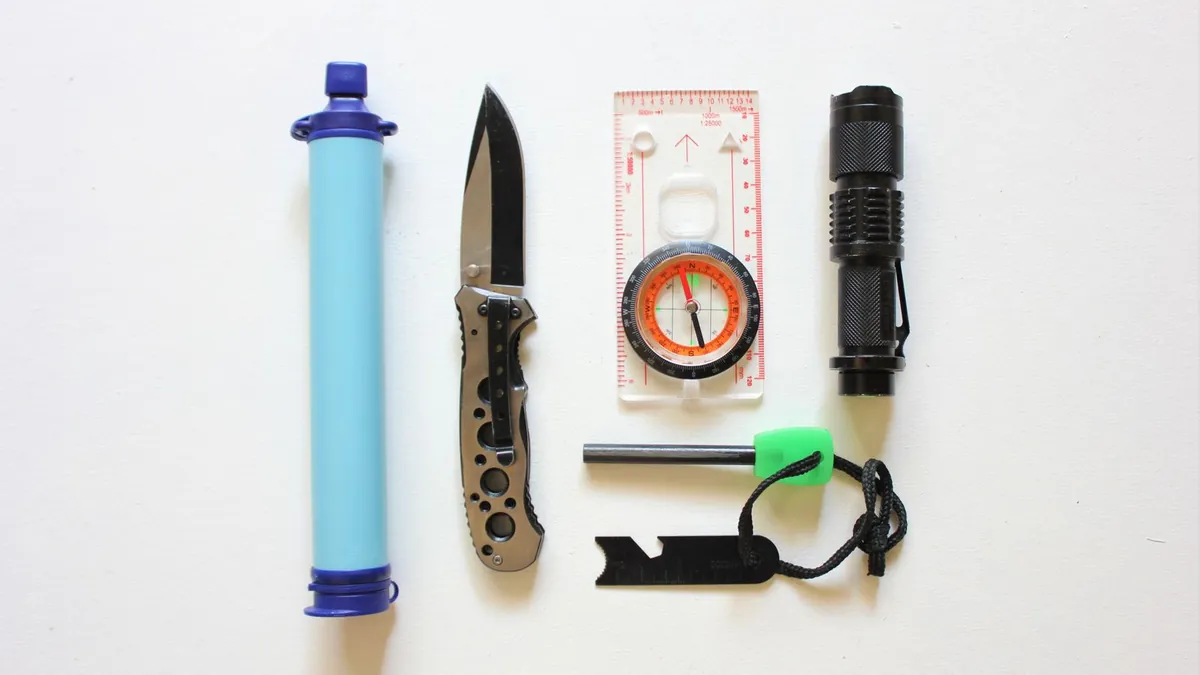 Emergency kit contents laid out on a wood floor next to an open backpack
