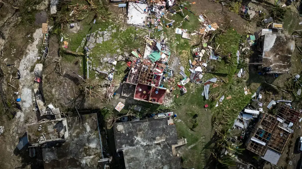 Aerial view of houses with roofs torn off and debris scattered after a hurricane