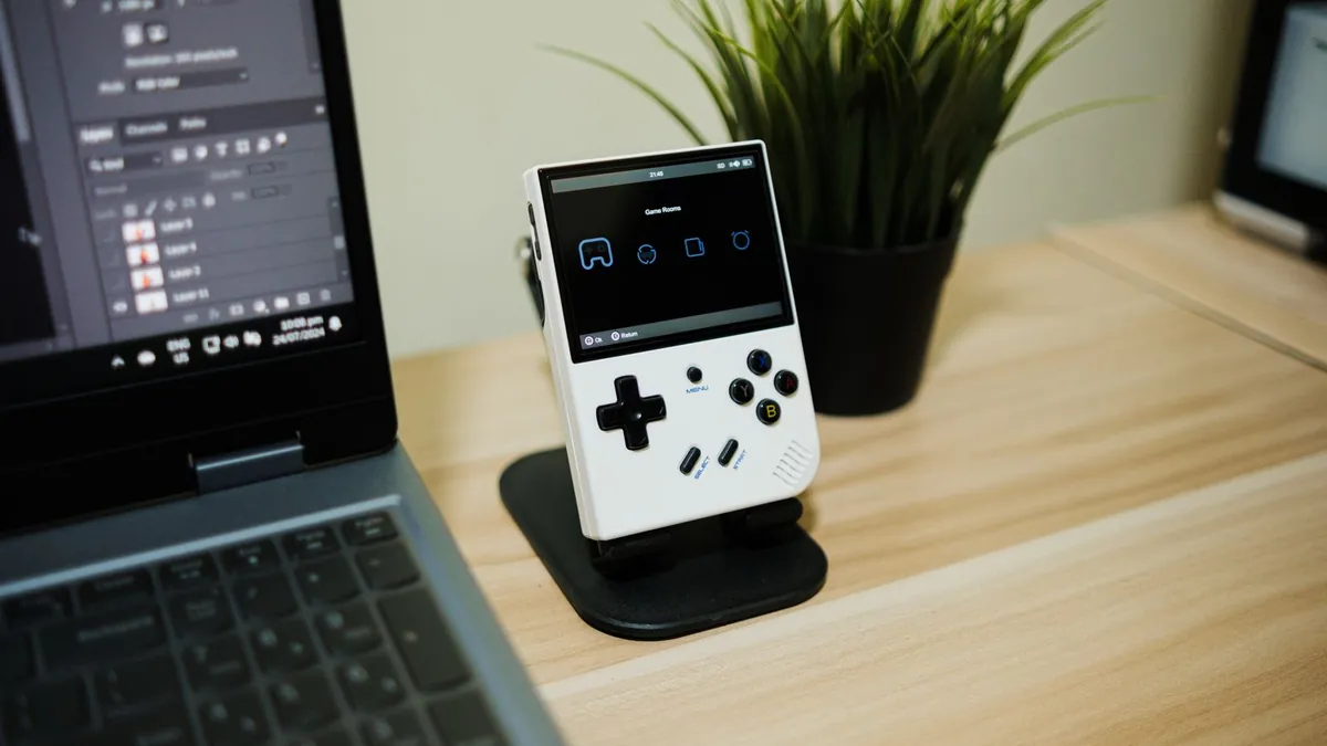 A handheld device with a small keyboard and screen resting on a map with a coffee mug